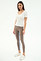 A woman faces forward wearing the SPLITS59 Ashby Rib Short Sleeve in white, taupe striped spandex-blend leggings, and silver sneakers against a plain light background.