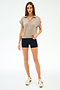 A woman stands facing forward against a plain white background, wearing the SPLITS59 Evie Fleece Sleeveless Polo in Latte, paired with black fitted shorts and beige sneakers.