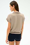 A woman stands with her back turned, wearing the SPLITS59 Evie Fleece Sleeveless Polo in Latte against a plain light background.