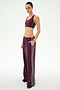 A person stands against a plain white background wearing SPLITS59′s Dallas French Terry Wide Leg Sweatpant in Dark Cherry/Black, paired with a matching maroon 100% cotton sports bra featuring white side stripes.