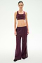 A person stands facing forward wearing SPLITS59’s Dallas French Terry Wide Leg Sweatpant in Dark Cherry/Black, featuring matching wide-leg track pants with white side stripes, crafted from soft 100% cotton, against a plain light background.