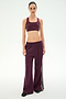 A person stands facing forward wearing SPLITS59’s Dallas French Terry Wide Leg Sweatpant in Dark Cherry/Black, featuring matching wide-leg track pants with white side stripes, crafted from soft 100% cotton, against a plain light background.