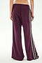 A person is shown from the back, standing against a plain background and wearing the SPLITS59 Dallas French Terry Wide Leg Sweatpant in Dark Cherry/Black—a loose-fitting pair of 100% cotton maroon pants featuring black and white side stripes.