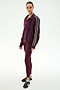 A person stands in a studio against a plain white background, wearing the SPLITS59 Goldie French Terry Oversized Half Zip in Dark Cherry/Black—an oversized zip-up jacket with striped sleeves crafted from soft cotton fabric—paired with matching maroon leggings and black sneakers.