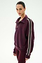 A person is wearing the SPLITS59 Goldie French Terry Oversized Half Zip in Dark Cherry/Black, featuring white-striped sleeves and matching leggings, crafted from soft cotton fabric, while standing against a plain light background.