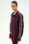 A person is wearing the SPLITS59 Goldie French Terry Oversized Half Zip in Dark Cherry/Black, featuring white-striped sleeves and matching leggings, crafted from soft cotton fabric, while standing against a plain light background.