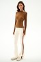 A woman stands facing forward wearing the SPLITS59 Isabelle Airweight Lite Mock Neck - Toffee/Creme and white pants with red and beige stripes, paired with light-colored sneakers.