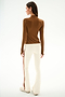 A person wears the Isabelle Airweight Lite Mock Neck - Toffee/Creme by SPLITS59, styled with white flared pants featuring a red side stripe, against a plain white background.
