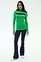 A woman faces forward wearing the SPLITS59 Lennon Rib Turtleneck in Grass/Indigo and navy flared pants with white sneakers—ideal for yoga or errands—against a plain white background.