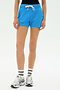 Model wearing the SPLITS59 Reena Sweatshort in Riviera, paired with white athletic socks and white sneakers, standing against a plain white background.