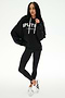 A person stands against a plain white background wearing the SPLITS59 Stella French Terry Oversized Hoodie in black, paired with black leggings and white sneakers.
