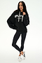 A person stands against a plain white background wearing the SPLITS59 Stella French Terry Oversized Hoodie in black, paired with black leggings and white sneakers.