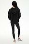 A person stands with their back to the camera, wearing the SPLITS59 Stella French Terry Oversized Hoodie in black, paired with black leggings featuring a white stripe and white sneakers, set against a plain white background.