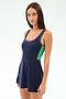 A woman models the SPLITS59 Martina Rigor Color Block Dress in Indigo/Spearmint, a navy sleeveless tennis dress with white trim and green side stripe, crafted from a stretchy nylon spandex blend for comfort and ease of movement against a white background.