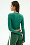 A woman with straight brown hair wears the SPLITS59 Louise Rib Long Sleeve Crop in Arugula, paired with matching green pants featuring a white stripe. She poses with her back to the camera against a plain light background.