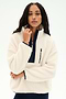 A woman wearing the SPLITS59 Reese Sherpa Half Zip Pullover in Creme/Indigo, made from 100% polyester fleece and featuring a zippered chest pocket, stands against a plain white background.