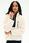 A woman wearing the SPLITS59 Reese Sherpa Half Zip Pullover in Creme/Indigo, made from 100% polyester fleece and featuring a zippered chest pocket, stands against a plain white background.