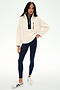 A person stands against a plain white background wearing the SPLITS59 Reese Sherpa Half Zip Pullover in Creme/Indigo, made from 100% polyester, paired with navy leggings and white sneakers.