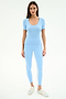 A woman stands facing forward in the SPLITS59 Ashby Rib Short Sleeve in Skylight with matching leggings featuring a side stripe, made from a soft modal-spandex blend, styled with silver sneakers against a plain white background.