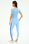 A woman faces away, wearing the SPLITS59 Ashby Rib Short Sleeve in Skylight and matching leggings with a dark blue side stripe, paired with white sneakers against a plain white background.