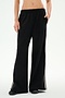 A person wearing the SPLITS59 Dallas French Terry Wide Leg Sweatpant in Black/Lentil, crafted from soft cotton fabric and featuring side stripes, stands with one hand in their pocket, shown from midriff to feet.