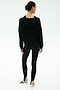 A woman stands with her back to the camera, wearing the SPLITS59 Joey Fleece Hoodie in black and matching leggings, paired with white sneakers, against a plain white background.