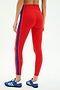 Model wears SPLITS59 Clare High Waist Rigor 7/8 leggings in Lotus Red/Cobalt, featuring a vertical blue stripe and made from performance fabric—ideal for workouts. Paired with blue athletic shoes, shown against a plain background.