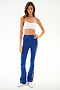 A woman in a white spandex crop top, Raquel High Waist Supplex Flare - Cobalt/Creme by SPLITS59, and silver sneakers stands against a plain white background.