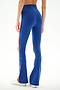 Model wearing SPLITS59 Raquel High Waist Supplex Flare - Cobalt/Creme pants with white sneakers, shown from the back against a plain background.