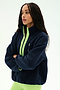A woman stands with arms crossed against a plain white background, wearing the SPLITS59 Reese Sherpa Half Zip Pullover in Indigo/Limeade—featuring a soft polyester sherpa material and a neon green zipper—paired with neon green leggings.