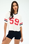 A woman stands against a white background wearing the SPLITS59 Rex Varsity Jersey V-Neck in white with number 59, paired with black viscose shorts.