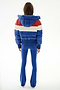 Person facing away, wearing the SPLITS59 Aspen Puffer Jacket - Cobalt/Creme with a hood and bright blue flared pants, standing against a plain white background.