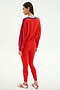 A woman stands sideways against a white background, wearing the SPLITS59 Ellie Fleece V Neck Sweatshirt in Lotus Red/Cobalt with matching red leggings and white Adidas sneakers featuring red stripes.