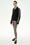 Standing against a white background, the individual is wearing the SPLITS59 Goldie French Terry Oversized Half Zip in Black/Lentil, featuring striped sleeves and soft cotton fabric, paired with taupe leggings and black Adidas sneakers.