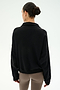 A woman with dark hair in a bun, wearing the SPLITS59 Goldie French Terry Oversized Half Zip in Black/Lentil and taupe leggings, stands facing away against a plain light background.