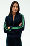 A woman with long dark hair poses in SPLITS59's Heritage Velour Bomber in Indigo/Grass, featuring green stripes—perfect for yoga warmups—against a plain white background.