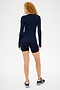 A person with curly red hair stands facing away on a white background, wearing the Louise Rib Long Sleeve - Indigo by SPLITS59, along with black shorts and sneakers.