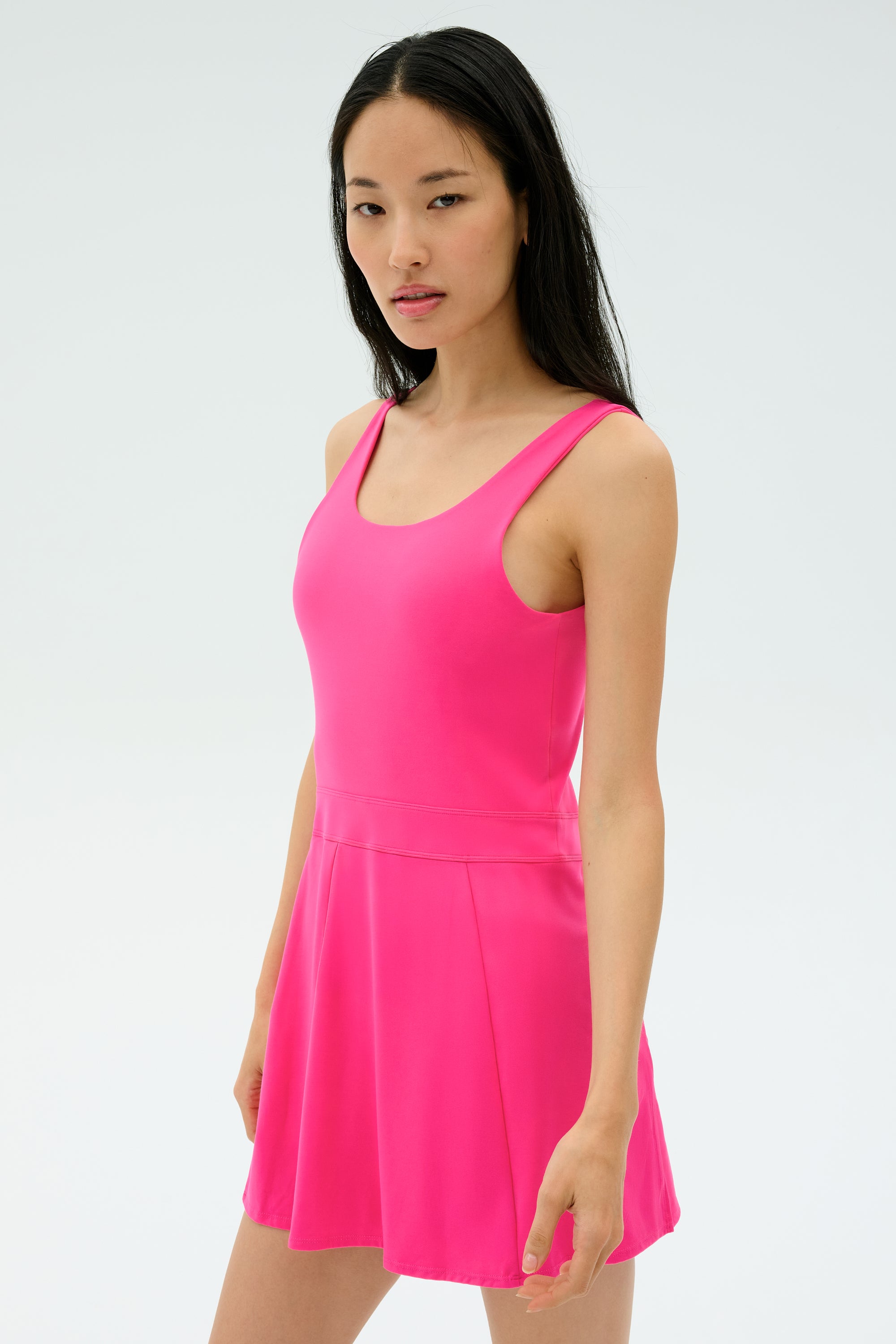 A person with long dark hair wears the SPLITS59 Martina Rigor Dress in Berry, standing against a plain light background.