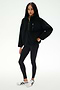 A woman wears the SPLITS59 Reese Sherpa Half Zip Pullover in black, styled with black leggings and white sneakers, standing against a plain white background.