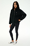 A woman wears the SPLITS59 Reese Sherpa Half Zip Pullover in black, styled with black leggings and white sneakers, standing against a plain white background.