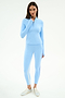 A woman poses against a white background wearing the SPLITS59 Tess Rigor Half Zip Waist Length - Skylight top with matching leggings, both in soft nylon spandex, paired with metallic sneakers.