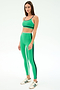 A woman in SPLITS59's Sam High Waist Rigor 7/8 leggings in Spearmint/Indigo, styled with a matching sports bra and white sneakers, stands against a plain light background.