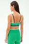 A woman stands facing away, wearing the SPLITS59 Eva Rigor Double Strap Bra in Spearmint/Indigo and matching green leggings.