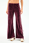 A person wearing SPLITS59 Heritage Velour Pant in Dark Cherry/White, featuring high-waisted, wide-leg design with side stripes and a spandex blend for stretch, paired with beige sneakers against a plain background.