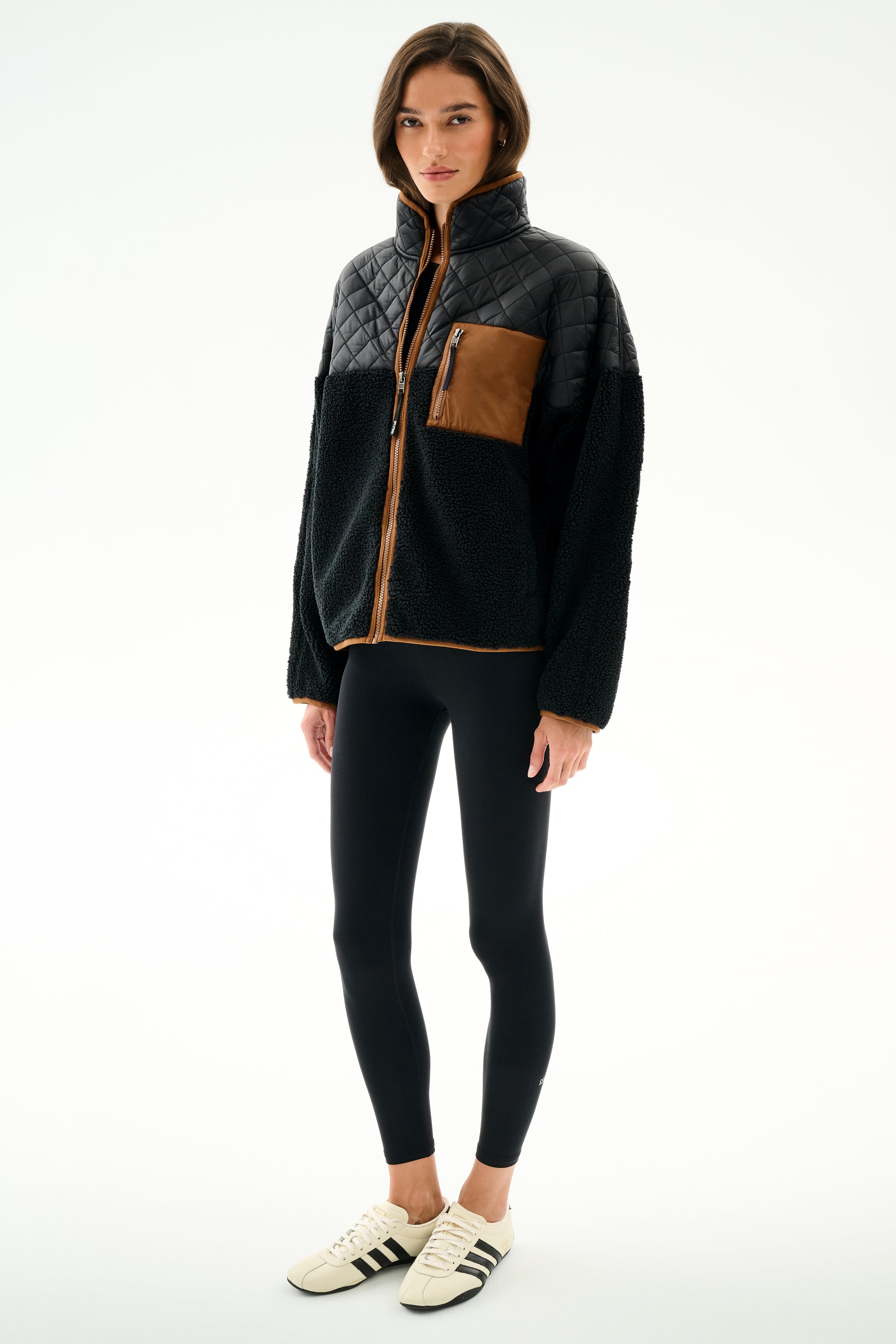 Woman wearing the SPLITS59 Skylar Sherpa Jacket - Black/Toffee with black leggings and white sneakers, standing against a plain white background.