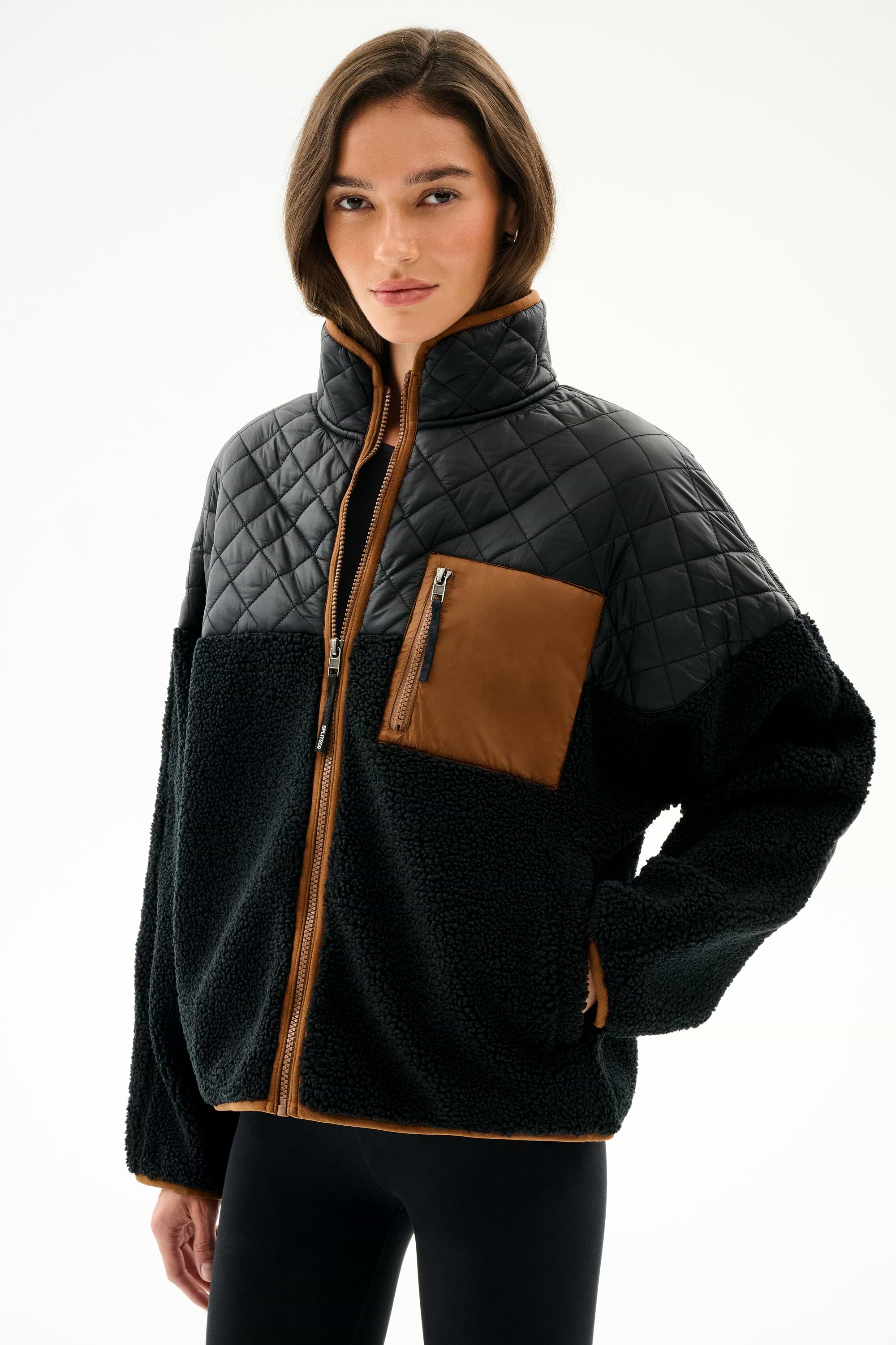 Person wearing the SPLITS59 Skylar Sherpa Jacket - Black/Toffee, a black and brown zip-up with high collar, made from 100% polyester, against a white background.