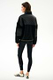 A person stands facing away in a SPLITS59 Skylar Sherpa Jacket - Black/Toffee, black leggings, and white Adidas sneakers with black stripes against a plain white background.