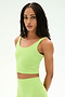 A person with long braided hair wears the SPLITS59 Sprint Rigor Bralette in Limeade—crafted from soft, stretchy nylon spandex—as they stand against a plain light background, looking at the camera.