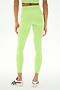 A person is seen from the back, standing against a plain background while wearing SPLITS59 Sprint High Waist Rigor 7/8 leggings in Limeade—a high-waisted, light green style crafted from stretchy nylon-spandex fabric—paired with white sneakers.