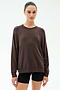 A person stands facing forward, wearing the SPLITS59 Andie Oversized Fleece Sweatshirt in Dark Chocolate and black shorts against a plain light background.
